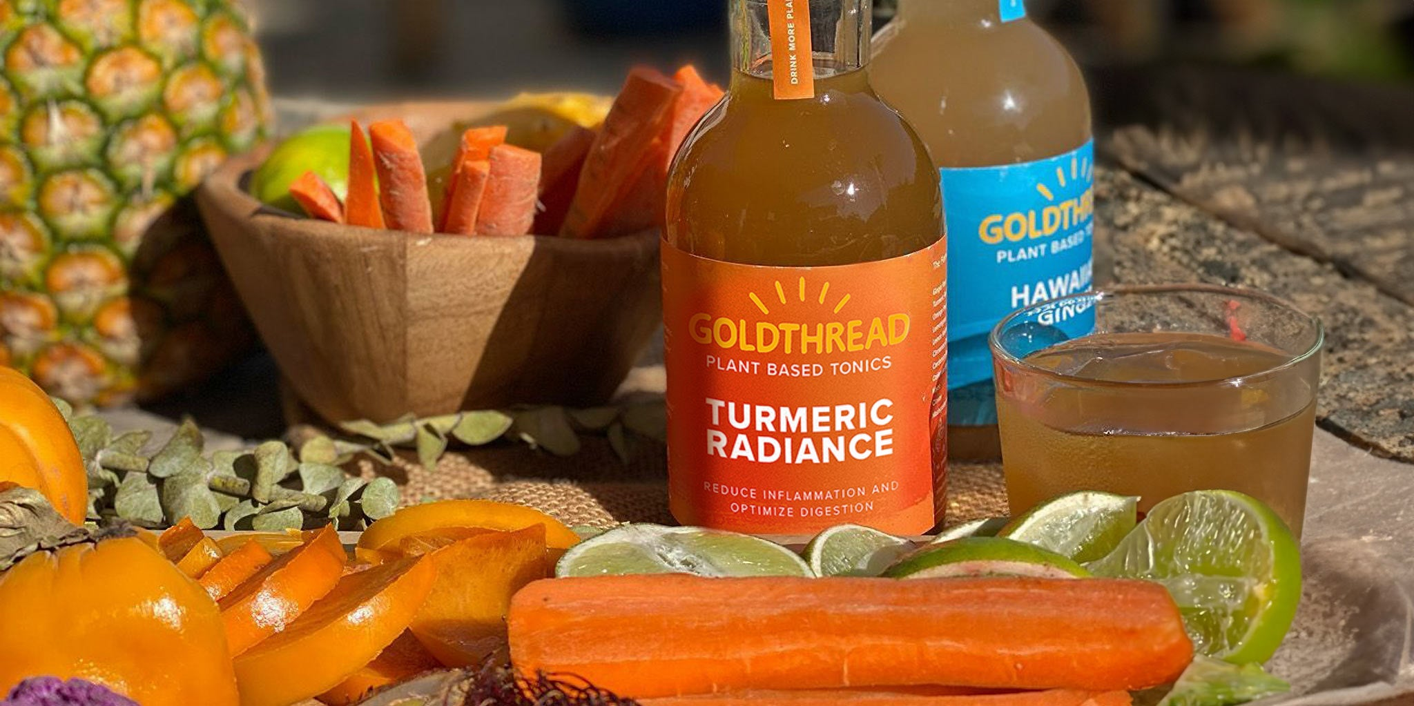 A woman enjoys a sandwich and pizza outdoors, with water and lemon slices. Thanks to Goldthread tonics, they can enjoy their meal with nourished gut health.
