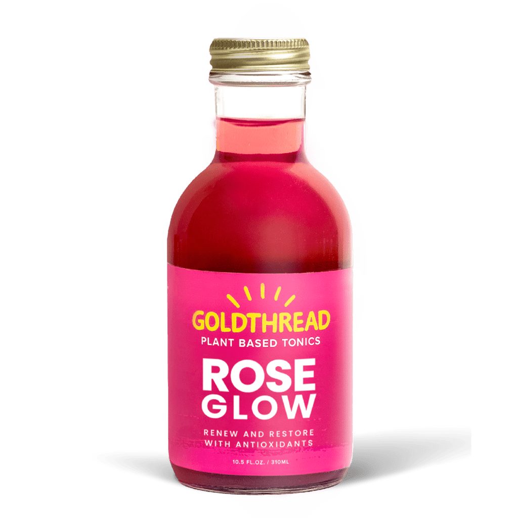 A glass bottle with a gold cap containing 10.5 fl oz (300 ml) of pink liquid. The pink label identifies the drink as Goldthread's Rose Glow plant-based tonic and features text reading "Renew and Restore with Antioxidants".